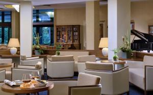 un vestíbulo del hotel con mesas, sillas y un piano en Hotel Garden Terme, en Montegrotto Terme