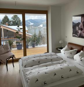 two beds in a bedroom with a large window at Tegernsee - Seeblick, Terrasse, Berge in Tegernsee