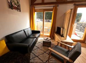 a living room with a leather couch and a television at Petit Chalet Montagne in Briançon