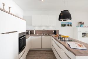 a white kitchen with white cabinets and a sink at Appartement "Mondstein" mit Penthouseflair - Oase am Haff in Garz-Usedom