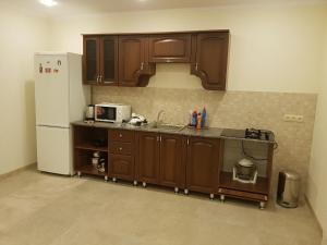 a kitchen with wooden cabinets and a white refrigerator at Домик из двух комнат + кухня столовая с удобствами, со своим двориком под ключ in Sukhum