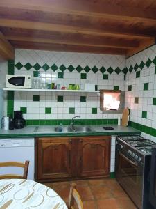 una cocina con azulejos verdes y blancos en la pared en Cottage 2 personnes, en Lormes