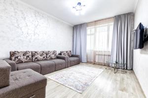 a living room with a couch and a tv at Апартаменты Променад экспо 269 in Astana