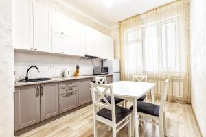 een keuken met witte kasten en een tafel en stoelen bij Апартаменты Променад экспо 269 in Astana