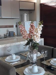 un jarrón de flores en una mesa con platos y vasos en Apartamento Condomínio Sonhos da Serra - Bananeiras, en Bananeiras