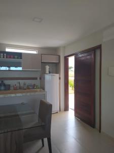 cocina con nevera, mesa y puerta en Apartamento Condomínio Sonhos da Serra - Bananeiras, en Bananeiras