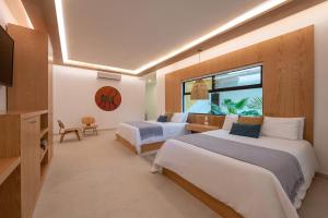 图卢姆Mayan Monkey Tulum - Social Hotel的有两张床和一扇窗户的酒店房间