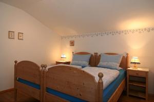 a bedroom with a wooden bed with blue sheets and pillows at Ferienwohnung Lauer in Schönau am Königssee