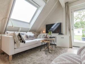 een woonkamer met een witte bank en een raam bij Vakantiewoningen Prelude & Etude in Wieringerwaard