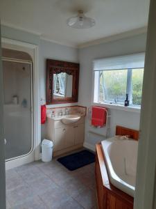 ein Badezimmer mit Badewanne, Waschbecken und Dusche in der Unterkunft Tui Glade Bed and Breakfast in Cambridge