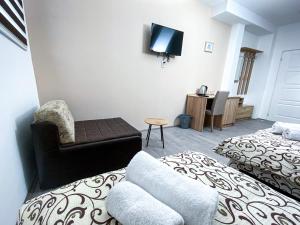 a room with two beds and a chair and a tv at Kiko apartmani in Zrenjanin