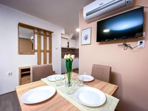 a dining room table with white plates and a television on the wall at Kiko apartmani in Zrenjanin