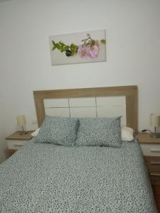 1 dormitorio con 1 cama con flores en la pared en Apartamento buena vista, en Almáchar