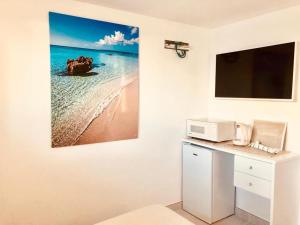 a kitchen with a microwave and a picture of the ocean at A 2 passi dal mare! in Es Pujols