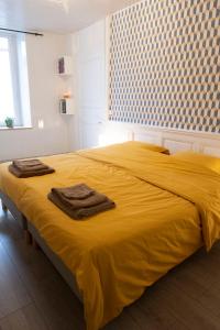 a bedroom with a yellow bed with towels on it at L'appart à Mimine in Chaudron-en-Mauges