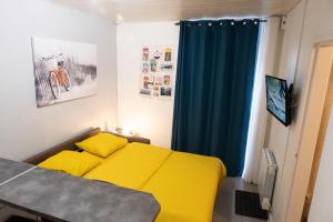 a bedroom with a yellow bed and a blue curtain at L'appart à Mimine in Chaudron-en-Mauges