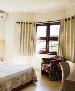 a bedroom with a bed and a chair and a window at Senior Parque Hotel in Santa Rosa