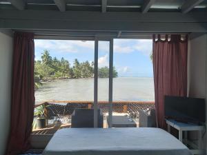 a bedroom with a bed and a view of the ocean at Bungalow blue lagon waterfront in Moorea