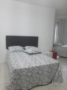 1 dormitorio con 1 cama con edredón blanco y negro en Locação de Loft no Sahy, en Mangaratiba