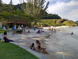 un grupo de personas jugando en el agua en una playa en Locação de Loft no Sahy, en Mangaratiba