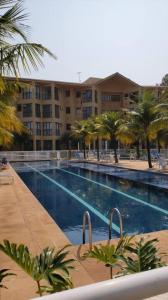 una piscina con palmeras y un gran edificio en Locação de Loft no Sahy, en Mangaratiba