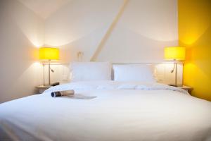 a bedroom with a large white bed with two lamps at La Ruche in Rolleboise