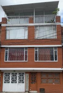 budynek z czerwonej cegły z oknami i balkonem w obiekcie Casa hotel Sports and Family w mieście Bogota