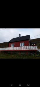 a red house with a white fence in front of it at Kongsfjord Paradise Holiday in Kongsfjord