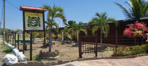 a sign in front of a fence with palm trees at Guille Bungalows in Canoas de Punta Sal