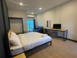 um quarto com uma cama e uma secretária com um computador em Sinai Hotel em Rayong