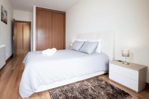 um quarto branco com uma grande cama branca e uma mesa de cabeceira em Aveiro Photo House - Bairro calmo no centro de Aveiro em Aveiro