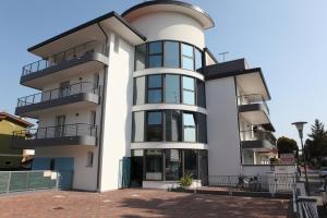 un grand bâtiment blanc avec des balcons dans l'établissement Villa Bruna, à Lignano Sabbiadoro