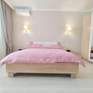 a bedroom with a pink bed with two lamps at квартира в Жилом комплексе Левитана,массив Радужный in Odesa