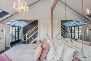 una camera da letto con un grande letto bianco con cuscini rosa di Manhattan Lofts a Città del Capo