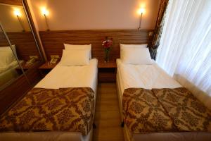 a room with two beds and a vase of flowers at Dort Mevsim Suit Hotel in Çanakkale