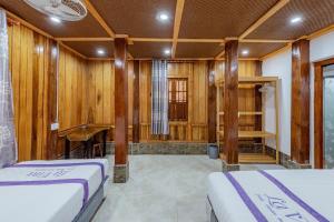 two beds in a room with wooden walls at Suncosy Central Resort in Phú Quốc