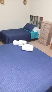dwa łóżka w pokoju z niebieską pościelą i komodą w obiekcie Hostal Doña María w mieście Valdemoro