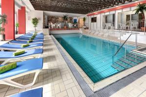 a swimming pool with lounge chairs in a hotel lobby at Ringhotel Parkhotel Witten in Witten +21 photos