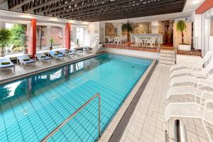 a large swimming pool with chairs and a table at Ringhotel Parkhotel Witten in Witten