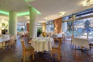 a dining room with tables and chairs and large windows at Ringhotel Parkhotel Witten in Witten