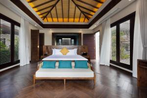 a bedroom with a large bed with blue pillows at Hoan My Resort - Ninh Chu in Phan Rang