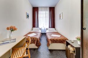 a hotel room with two beds and a desk at Acme Petrogradskaya in Saint Petersburg