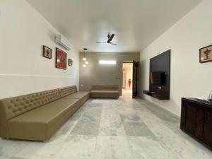 sala de estar con sofá y TV de pantalla plana en Casa Blanca - A Boutique Resort, en Ahmedabad