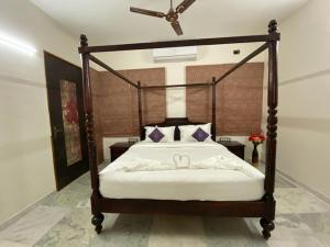 a bedroom with a bed with a wooden frame with two bows at Casa Blanca - A Boutique Resort in Ahmedabad