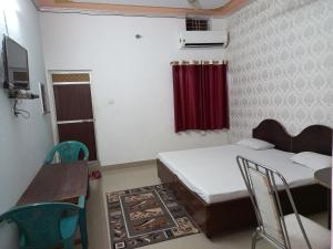 um pequeno quarto com 2 camas, uma mesa e cadeiras em vindhyvasini guest house em Kushinagar