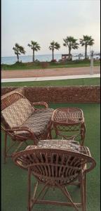 two wicker chairs and a table in front of the ocean at Chalet Porto South Beach - Beach Front Sea View in Ain Sokhna