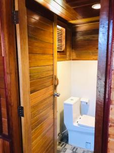 a bathroom with a toilet and a wooden door at ไร่นาบัวหลวง คาเฟ่ & ฟาร์มสเตย์ RaiNa BuaLuang Cafe & Farm Stay in Ban Na No