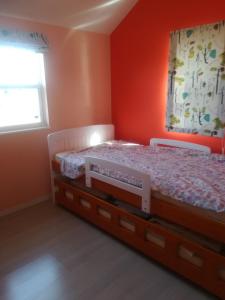 a bedroom with orange walls and a bed and a window at Guest House Tomida in Ena