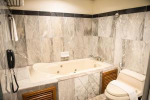 a bathroom with a tub and a toilet at The Twin Lotus Hotel in Nakhon Si Thammarat