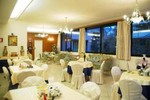un ristorante con tavoli e sedie bianchi e finestre di Hotel Flowers a Montecatini Terme